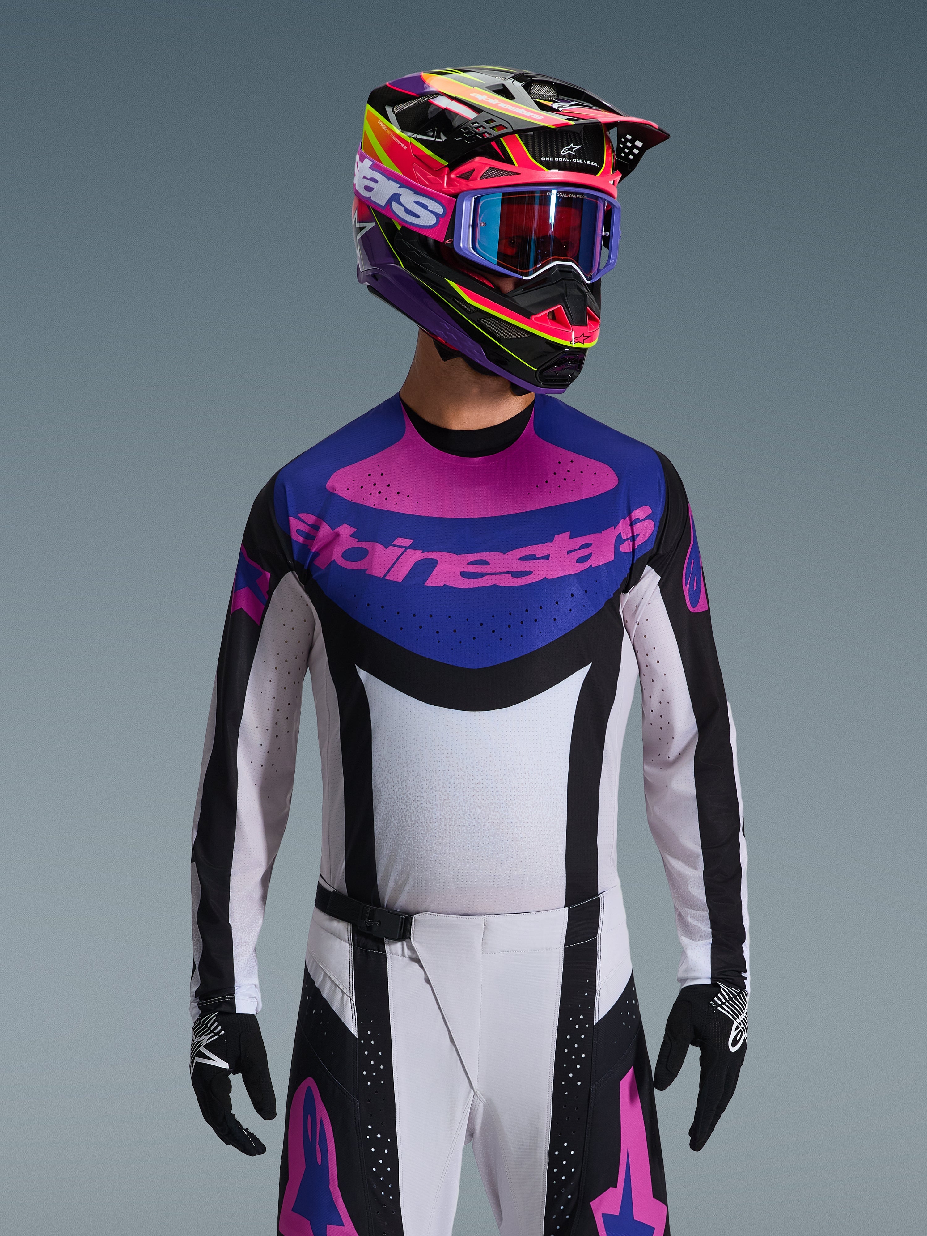 Alpinestars 2026 Techstar Knif Jersey, koszulka motocrossowa, czarna, jasnoszara i fioletowa, różowe logo Alpinestars na klatce piersiowej, noszona z pasującym kolorowym kaskiem i spodniami motocrossowymi, sportowy krój wyścigowy z laserowo wycinanymi perforacjami dla wentylacji