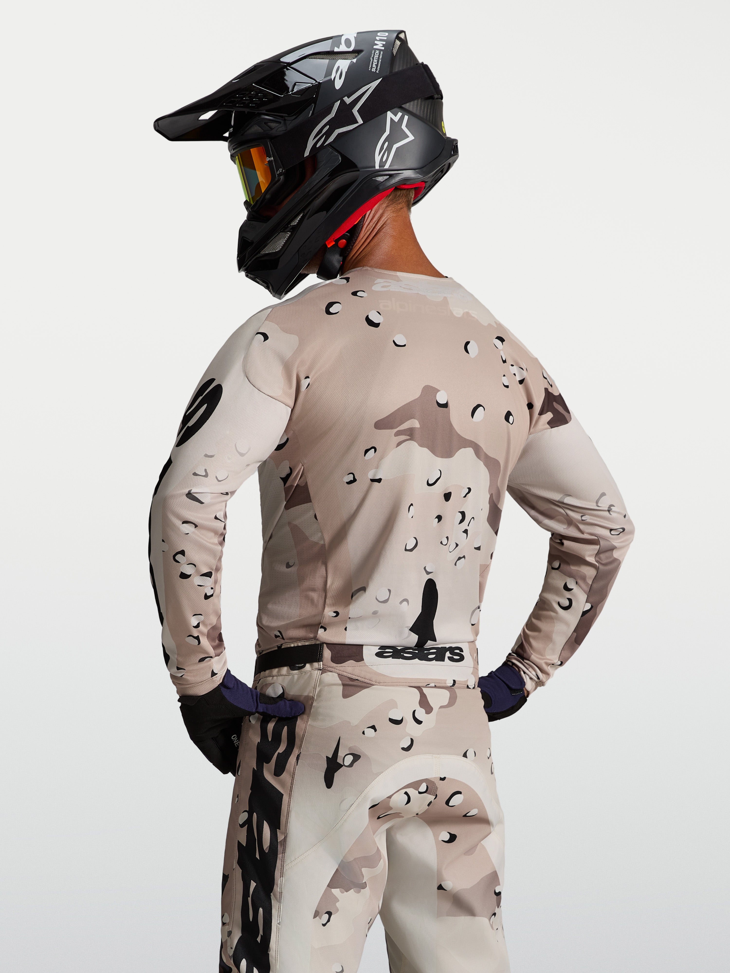 Alpinestars Racer Lone, męska koszulka motocrossowa, pustynne moro i czarna, widok od tyłu na modela, lekka i oddychająca konstrukcja z polifabryku o wyścigowym kroju.