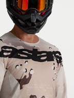 Alpinestars koszulka Racer Lone, męska koszulka motocrossowa, pustynny kamuflaż i czerń, zbliżenie na modela w kasku.
