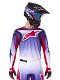 Alpinestars 2025 Fluid Wurx Jersey, koszulka motocrossowa, fioletowo-biały gradient, czerwone logo z gwiazdą i akcenty, sportowy krój, noszona z pasującymi spodniami, czarnym kaskiem i czerwonymi rękawicami