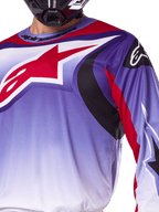 Alpinestars 2025 Fluid Wurx Jersey, koszulka motocrossowa, fioletowa z jaskrawoczerwonymi elementami, zbliżenie na zawodnika w koszulce z dużym czerwonym logo gwiazdy Alpinestars na piersi, czarne i czerwone zakrzywione akcenty graficzne, sportowy krój do wyścigów off-road