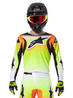 Koszulka Alpinestars Fluid Wurx 2025, koszulka motocrossowa, neonowożółta, pomarańczowa i biała, noszona z dopasowanymi spodniami i czarnym kaskiem z czerwonymi goglami, kompletny zestaw odzieży MX na motocykliście