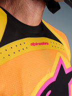 Alpinestars 2026 Techstar Nomur Jersey, koszulka motocrossowa, pomarańczowo-żółto-różowa, zbliżenie na detale klatki piersiowej i kołnierzyka, laserowo wycinana wentylacja, różowe logo i oddychająca tkanina siateczkowa