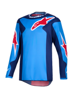 Alpinestars 2026 Fluid Grid Jersey, koszulka motocrossowa, niebiesko-czerwona, duże czerwone logotypy gwiazdy Alpinestars, ciemnoniebieskie panele boczne, lekka konstrukcja z tkaniny poliestrowej z przedłużonym tyłem do jazdy terenowej