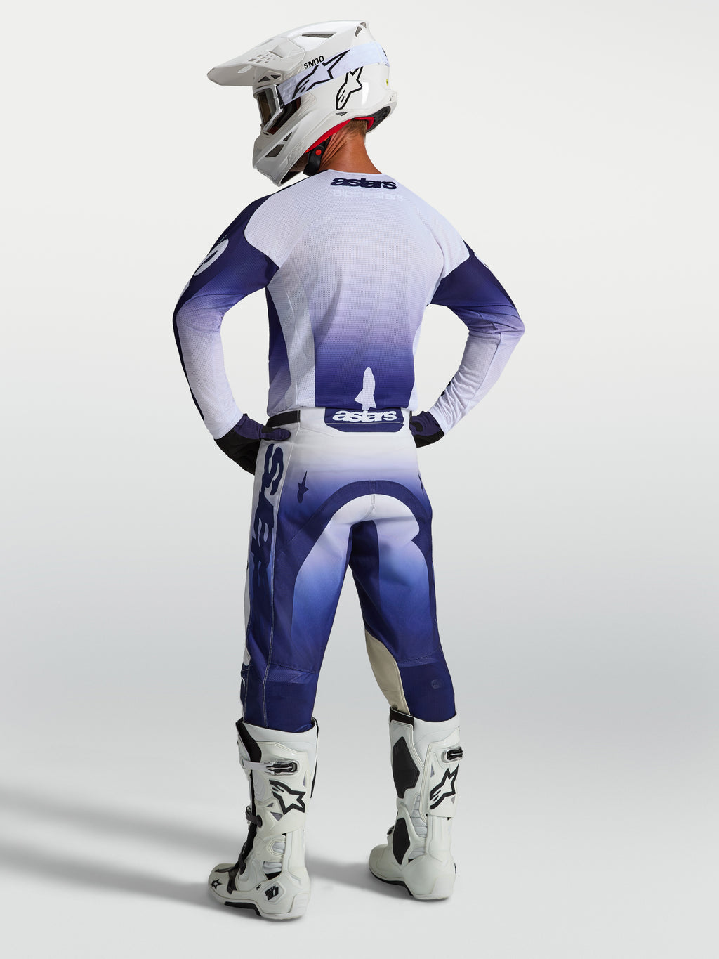 Alpinestars Racer Air Amber, zestaw odzieży motocrossowej, granatowa i biała siatkowa koszulka oraz spodnie, widok z tyłu na modelu w stroju wyścigowym.