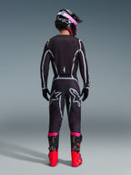Motocyklista motocrossowy widziany od tyłu w zestawie Alpinestars 2026 Fluid Apex Gear Set, czarna bluza i spodnie z szarymi geometrycznymi liniami i logo gwiazdy, czarny kask z różowymi akcentami, jaskrawoczerwone i czarne buty, kompletny strój wyścigowy