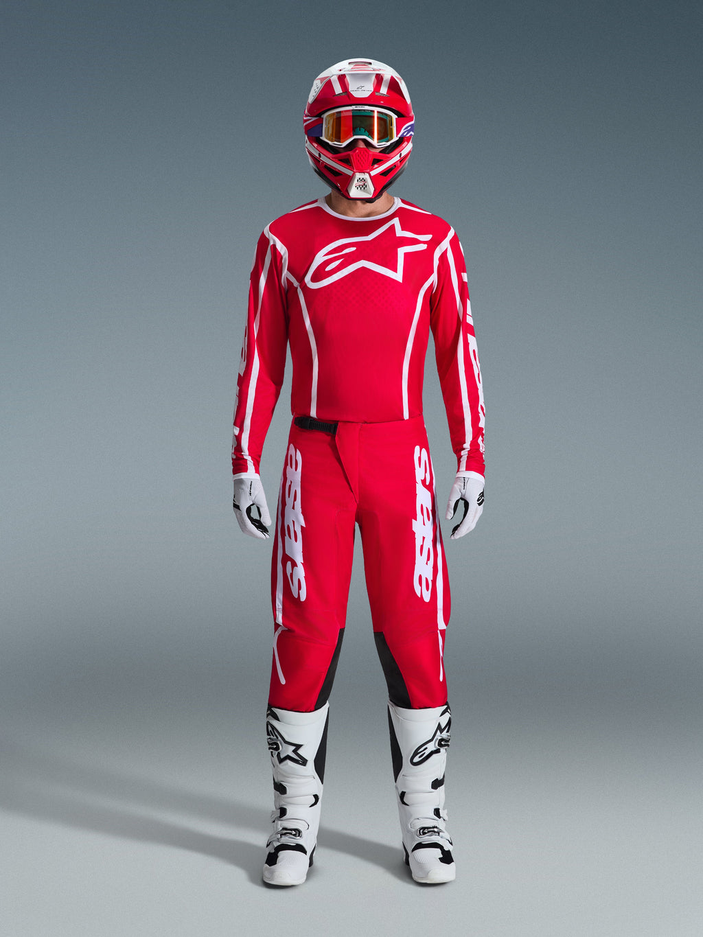 Alpinestars 2026 Fluid Apex Gear Set, strój motocrossowy, czerwony i biały, pełny zestaw wyścigowy zawierający czerwoną koszulkę z długim rękawem i białym logo gwiazdy, czerwone spodnie z białym brandingiem i czarnymi panelami na kolanach, białe buty z czarnymi akcentami, białe rękawice oraz pasujący czerwono-biały kask z goglami, kompletny ubiór do wyścigów off-road