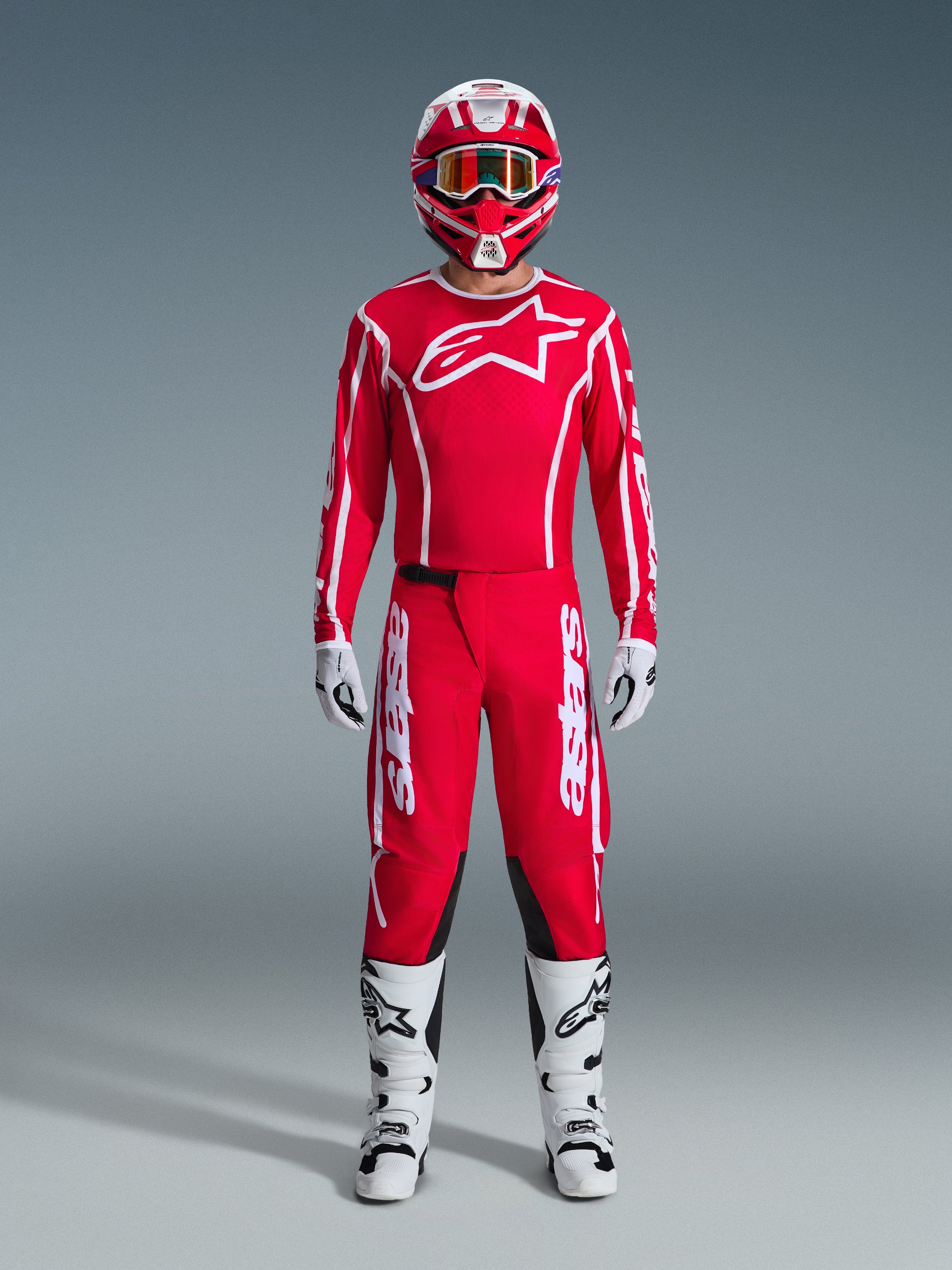 Alpinestars 2026 Fluid Apex Gear Set, strój motocrossowy, czerwony i biały, pełny zestaw wyścigowy zawierający czerwoną koszulkę z długim rękawem i białym logo gwiazdy, czerwone spodnie z białym brandingiem i czarnymi panelami na kolanach, białe buty z czarnymi akcentami, białe rękawice oraz pasujący czerwono-biały kask z goglami, kompletny ubiór do wyścigów off-road