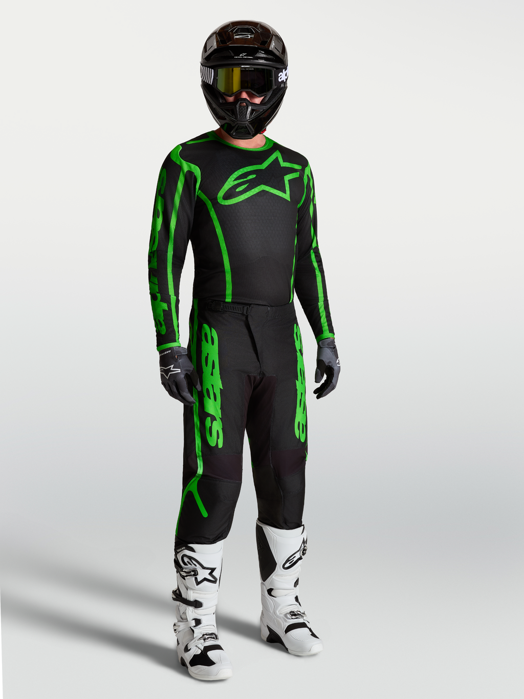 Alpinestars Spodnie Fluid Apex V2, męskie spodnie motocrossowe, czarne i zielone fluo, wytrzymały poliester 600D, ergonomiczny krój, widoczne w pełnym zestawie z białymi butami motocyklowymi.