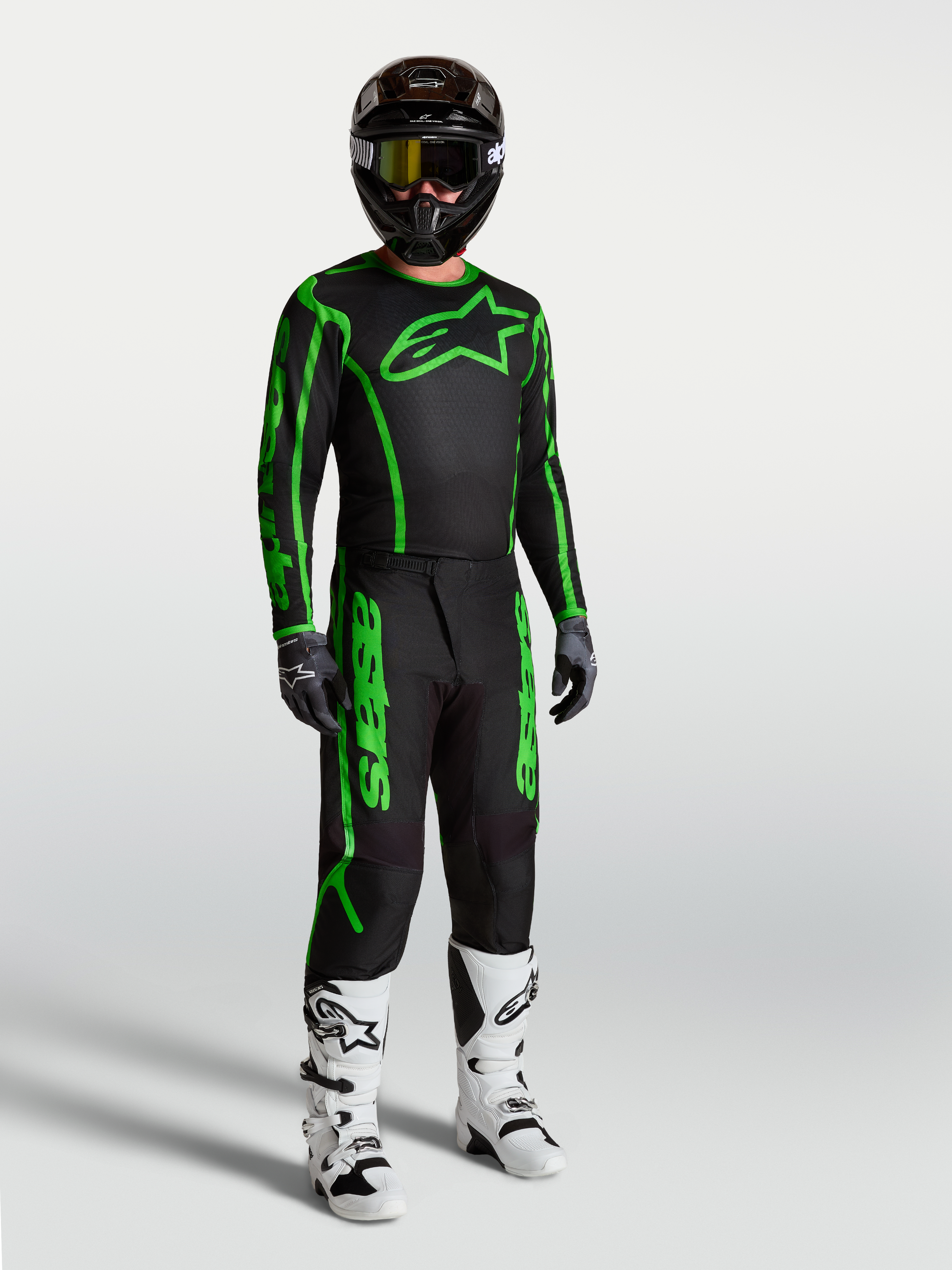 Alpinestars koszulka Fluid Apex V2, męska odzież motocrossowa, czarno-zielona fluo, na modelu z butami i spodniami.