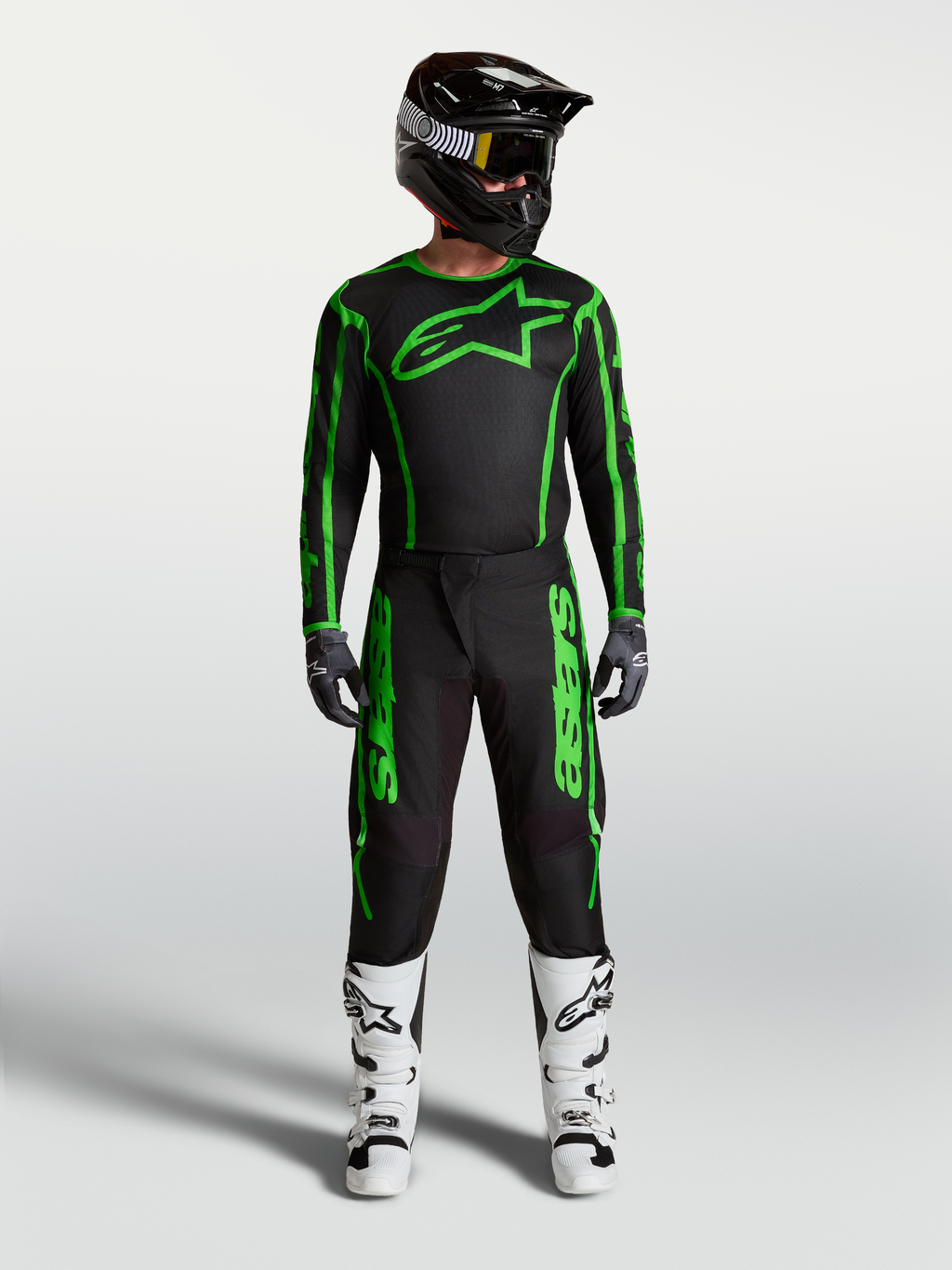 Męski zestaw Alpinestars Fluid Apex V2, czarno-zielona koszulka i spodnie motocrossowe oraz białe buty.