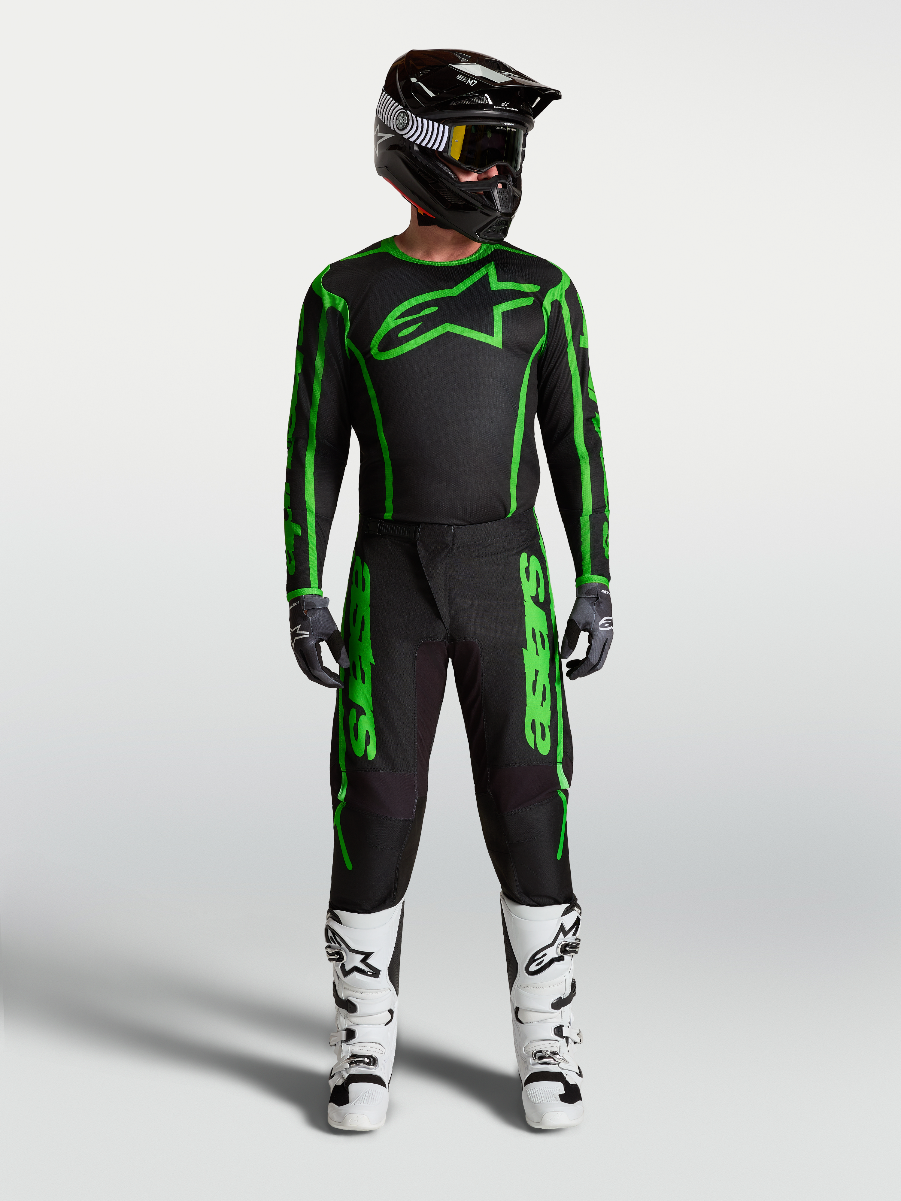Męski zestaw Alpinestars Fluid Apex V2, czarno-zielona koszulka i spodnie motocrossowe oraz białe buty.