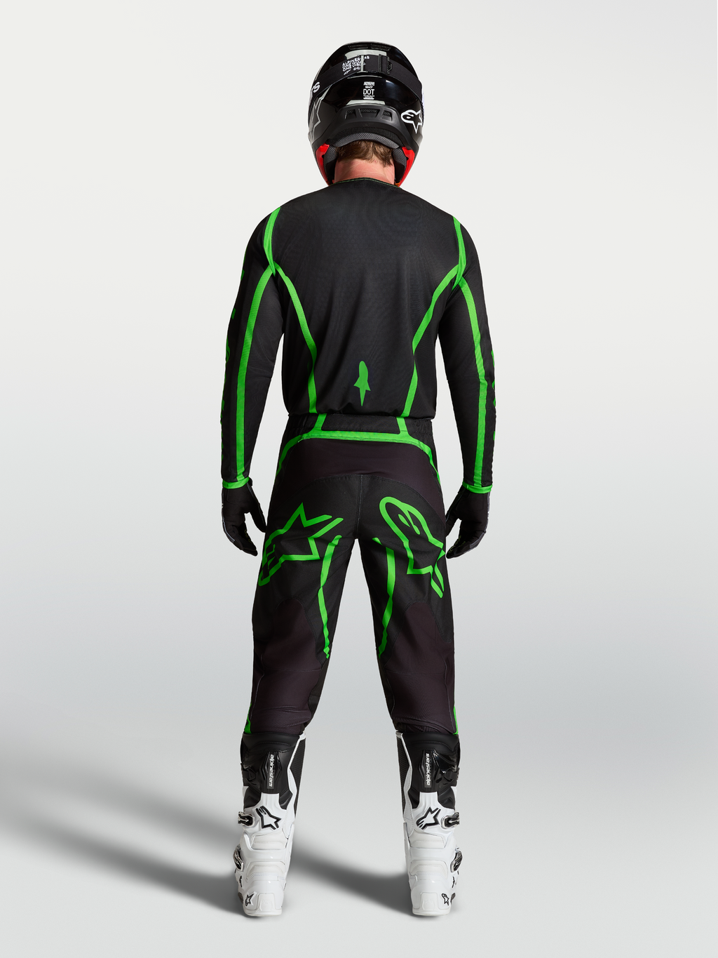 Alpinestars spodnie Fluid Apex V2, czarne i zielone fluo spodnie motocrossowe, widok z tyłu na motocykliście, białe buty