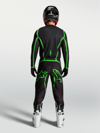 Alpinestars spodnie Fluid Apex V2, czarne i zielone fluo spodnie motocrossowe, widok z tyłu na motocykliście, białe buty