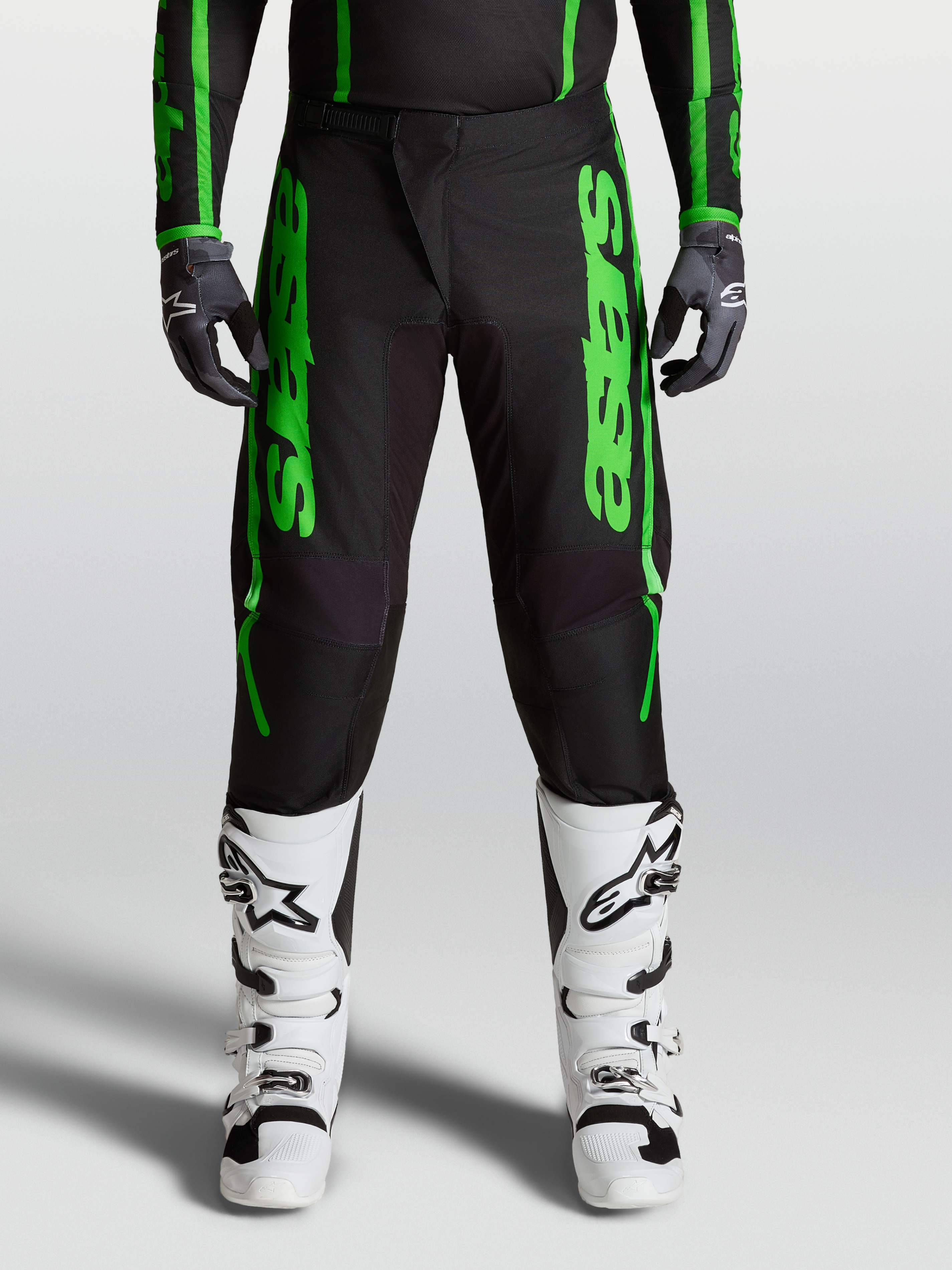 Spodnie Alpinestars Fluid Apex V2 2027, męska odzież motocrossowa, zielone i czarne, wzmocnione kolana i białe buty.