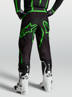 Spodnie Alpinestars Fluid Apex V2, męskie spodnie motocrossowe, czarne i jaskrawozielone, widok od tyłu na modelu w białych butach.