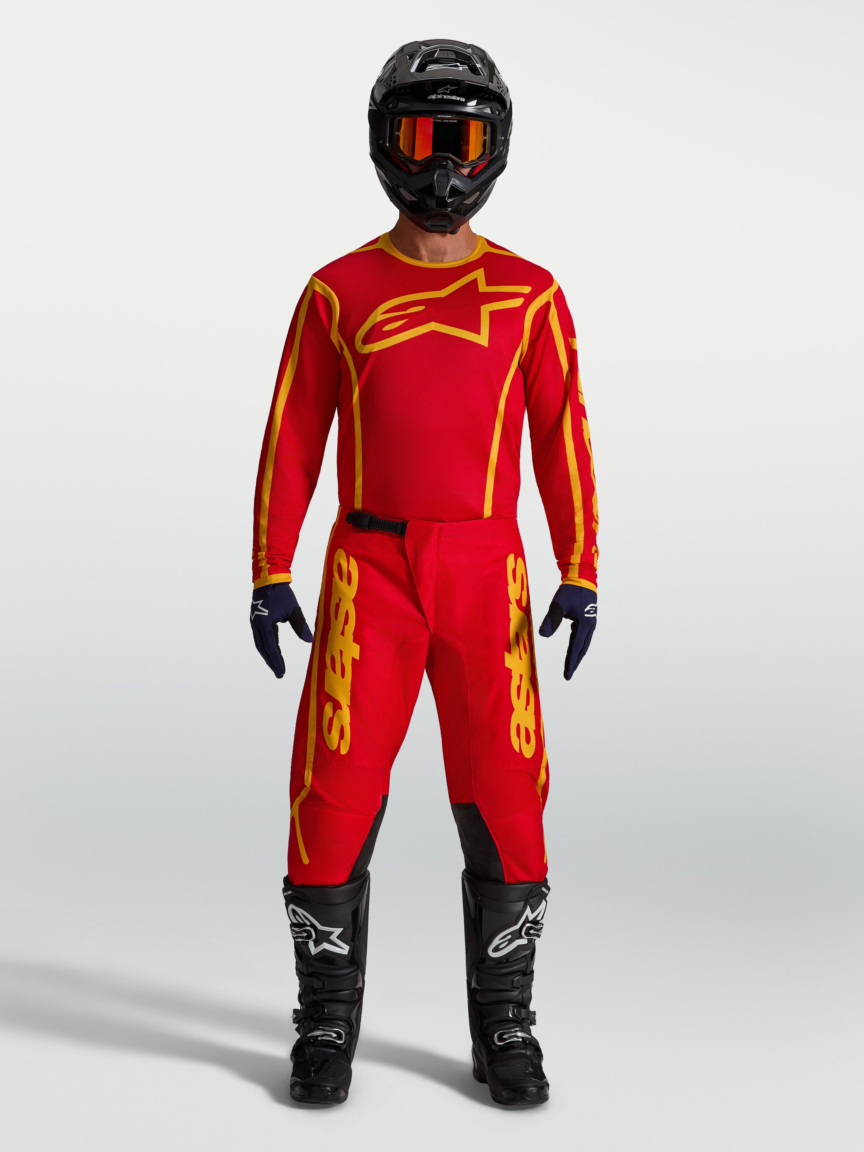 Alpinestars Koszulka Fluid Apex V2 i Fluid Apex V2 Gear Set, męska odzież motocrossowa, czerwona i złota, na modelu.