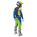 Zawodnik motocrossowy widoczny od tyłu w koszulce Alpinestars 2024 Racer Hoen w kolorze żółtym neonowym i granatowym, dopasowane spodnie motocrossowe i białe buty, pokazujący tylny design z czerwonymi logo, profesjonalny strój do wyścigów terenowych