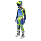 Alpinestars 2024 Racer Hoen Jersey, koszulka motocrossowa, żółta fluorescencyjna i granatowa, noszona przez motocyklistę z dopasowanymi spodniami, kaskiem i białymi butami, profesjonalny sprzęt wyścigowy do jazdy terenowej