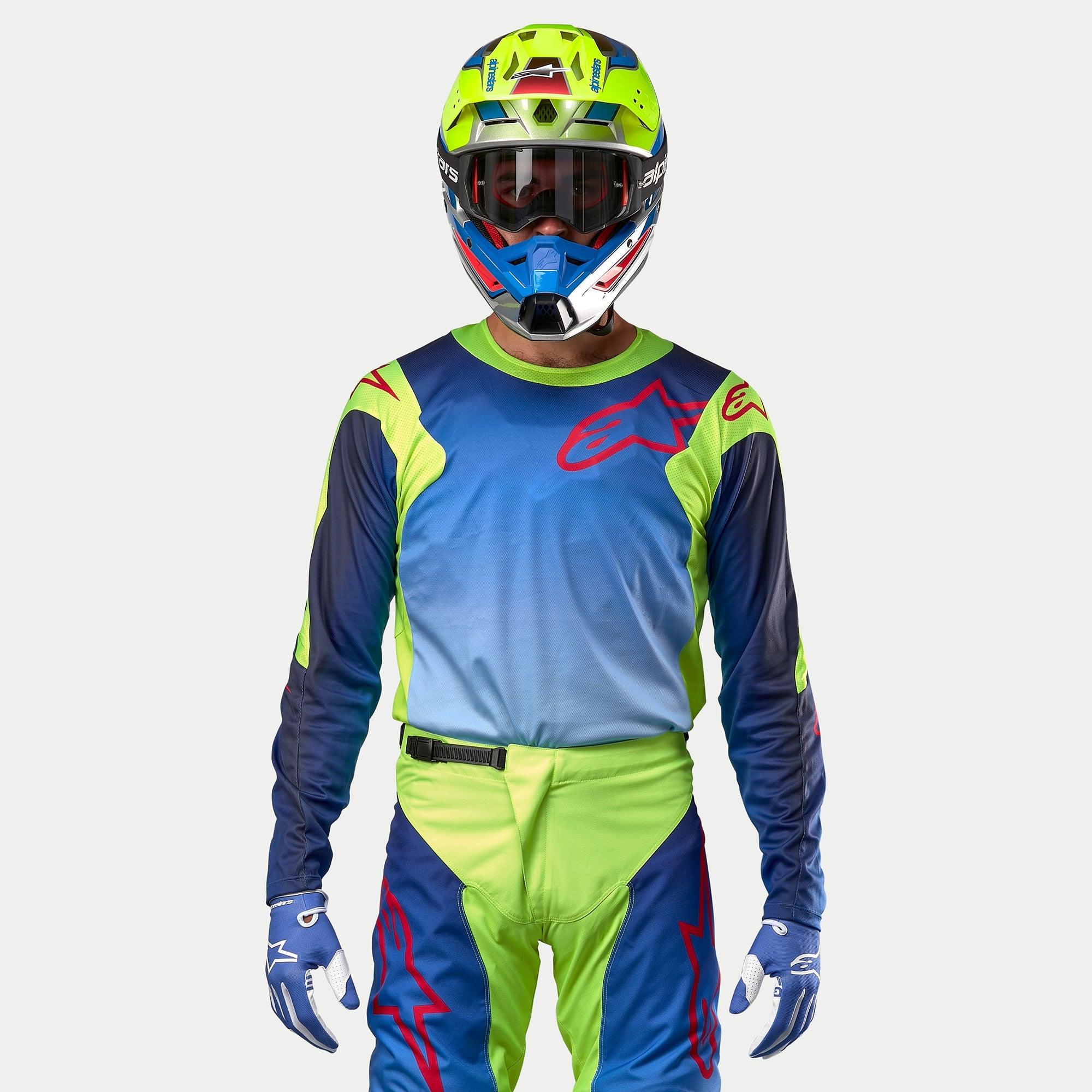 Alpinestars Racer Hoen Jersey 2024, koszulka motocrossowa, żółty neonowy i granatowy, widok z przodu na motocyklistę w pasującym kasku i stroju, duże czerwone logo na piersi, oddychające panele z siatki