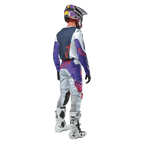 Zawodnik motocrossowy widziany od tyłu, ubrany w koszulkę Alpinestars 2024 Racer Hoen Jersey w kolorze Light Gray Hot Orange Black, granatowy panel tylny z pomarańczowym logo gwiazdy, fioletowe rękawy, pasujące spodnie wyścigowe i białe buty.