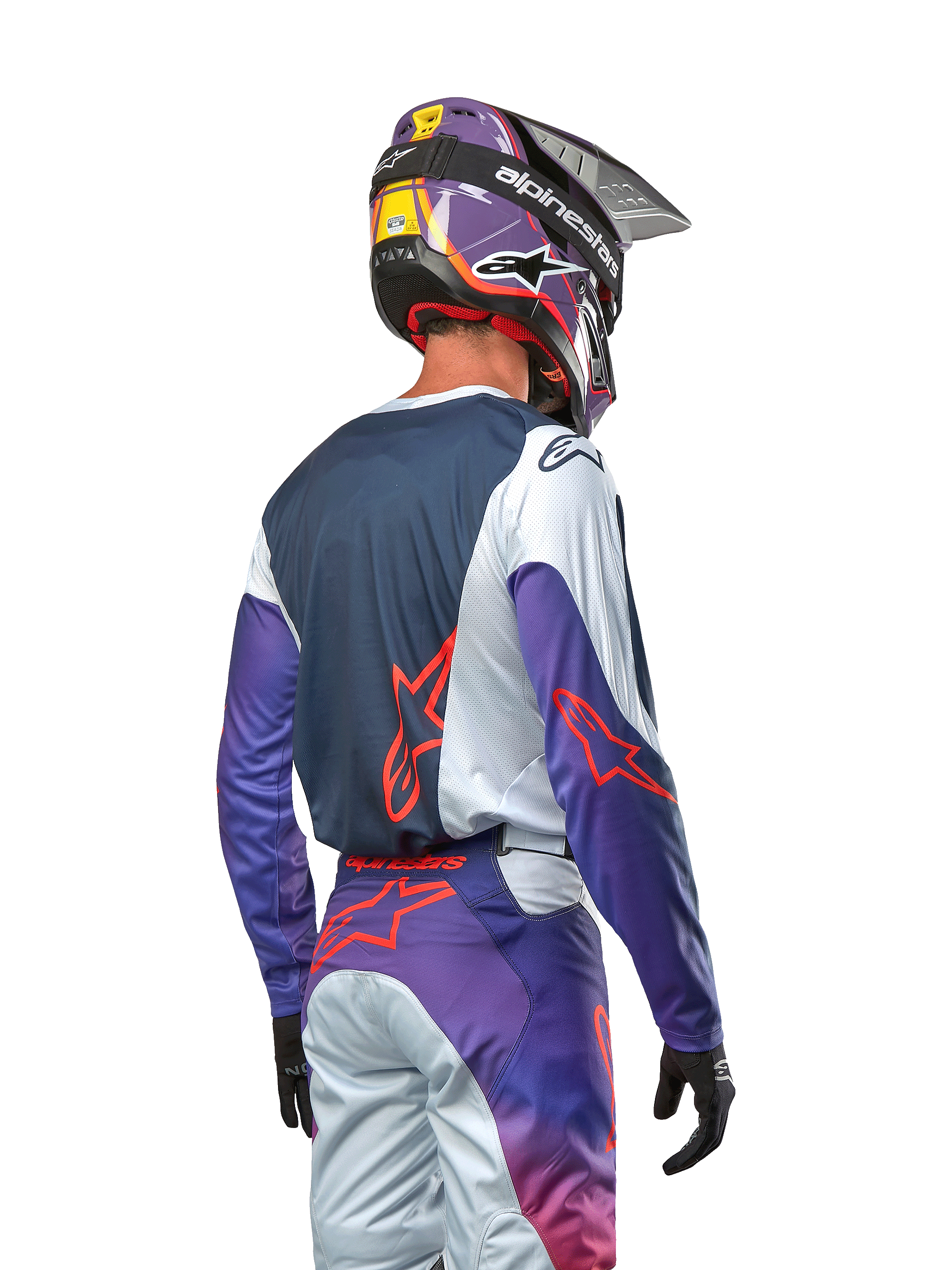 Zawodnik motocrossowy widziany od tyłu w koszulce 2024 Racer Hoen, granatowy panel tylny z jasnoszarymi ramionami i fioletowymi rękawami, jaskrawopomarańczowe logo Alpinestars, pasujące fioletowo-szare spodnie z fioletowym kaskiem motocrossowym, kompletny zestaw wyścigowy off-road