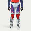 Alpinestars 2024 Racer Hoen Pants, spodnie motocrossowe, jasnoszare z fioletowymi i czerwonymi akcentami, czerwone logo na udach i ochraniacze kolan, białe buty motocyklowe, czarne rękawice, nowoczesny design sportowy