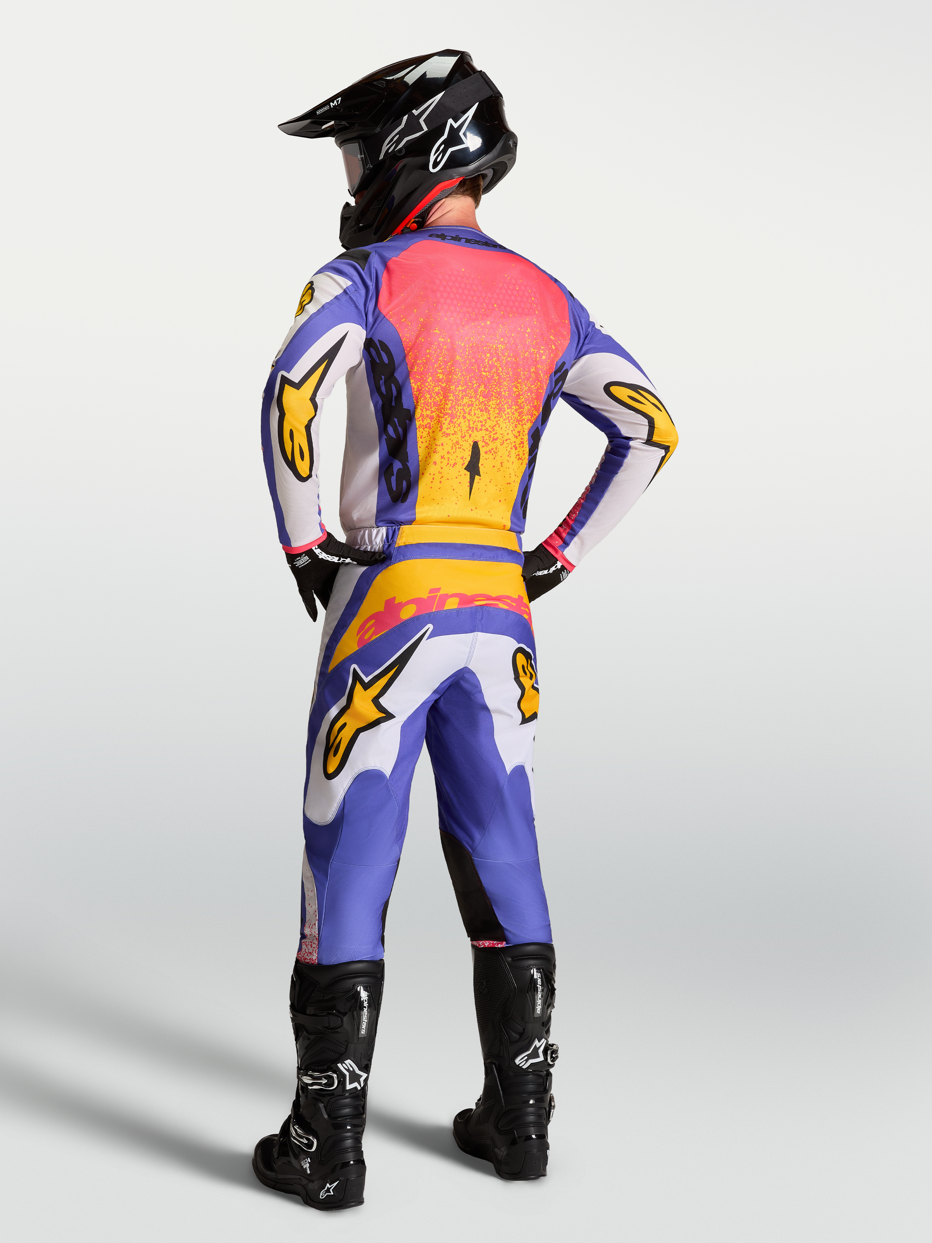 Zestaw Alpinestars Fluid Drag, koszulka i spodnie MX, męskie, niebieskie i liliowe ze złotym, widok z tyłu na modelu.