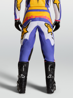 Alpinestars Fluid Drag Pants for motocross racing, view from behind, in Blue and Gold with stretch corduroy panels and reinforced seat, paired with black technical boots.