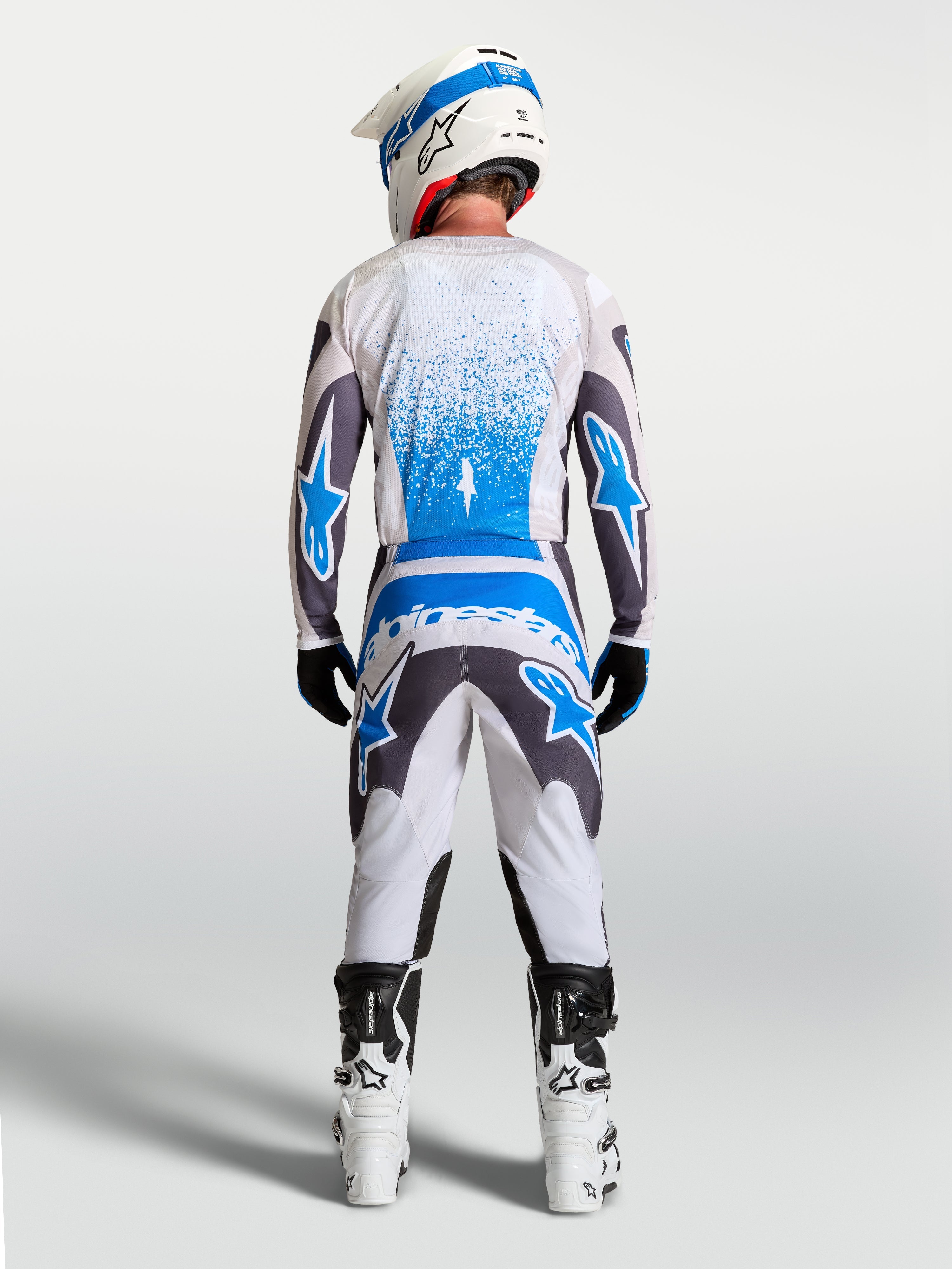 Alpinestars Fluid Drag Gear Set, męski zestaw odzieży MX, biały, szary i niebieski, widok od tyłu na koszulkę i spodnie o ergonomicznym kroju do jazdy motocrossowej
