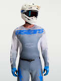 Koszulka Racer Amber, męska koszulka motocrossowa Alpinestars w kolorze szarym i niebieskim UCLA Blue, biały kask MX i gogle.