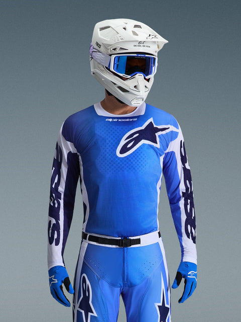 Koszulka Alpinestars 2026 Racer Air Portl w kolorze niebieskim i białym, koszulka motocrossowa o oddychającej, siateczkowej konstrukcji z wyrazistym logo gwiazdy, noszona przez motocyklistę z pasującymi spodniami, białym kaskiem i niebieskimi goglami, tworząca spójny zestaw odzieży do wyścigów terenowych.