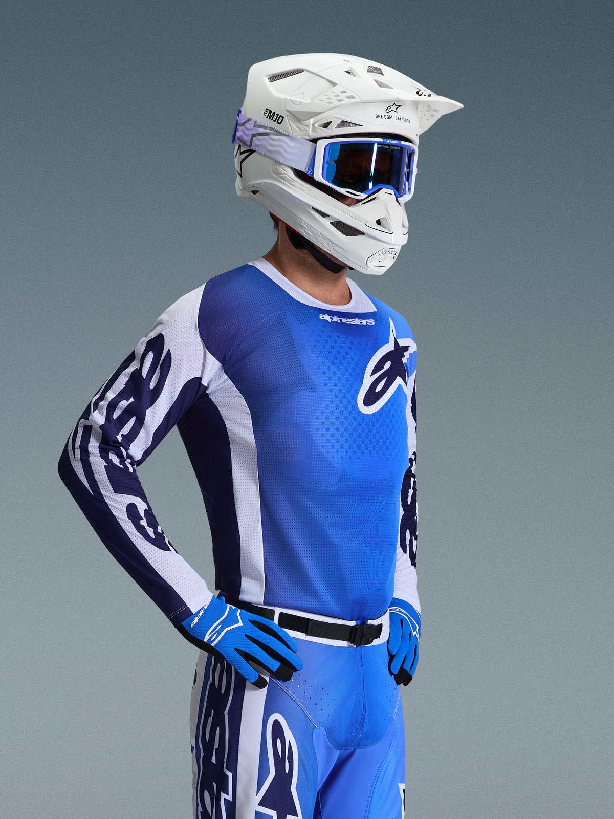 Alpinestars 2026 Racer Air Portl Jersey, koszulka motocrossowa, biało-niebieska (Ucla Blue), noszona z białym kaskiem, niebieskimi goglami i pasującymi rękawicami, przewiewna siatkowa konstrukcja do wyścigów terenowych w wysokich temperaturach