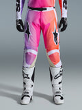 Alpinestars 2026 Racer Air Portl Pants, spodnie motocrossowe, gradient w intensywnych odcieniach fioletu, różu i pomarańczu, z wyraźnymi logotypami gwiazdy na udach, zestawione z białymi butami wyścigowymi i czarnymi rękawicami, zaprojektowane do wyczynowej jazdy terenowej