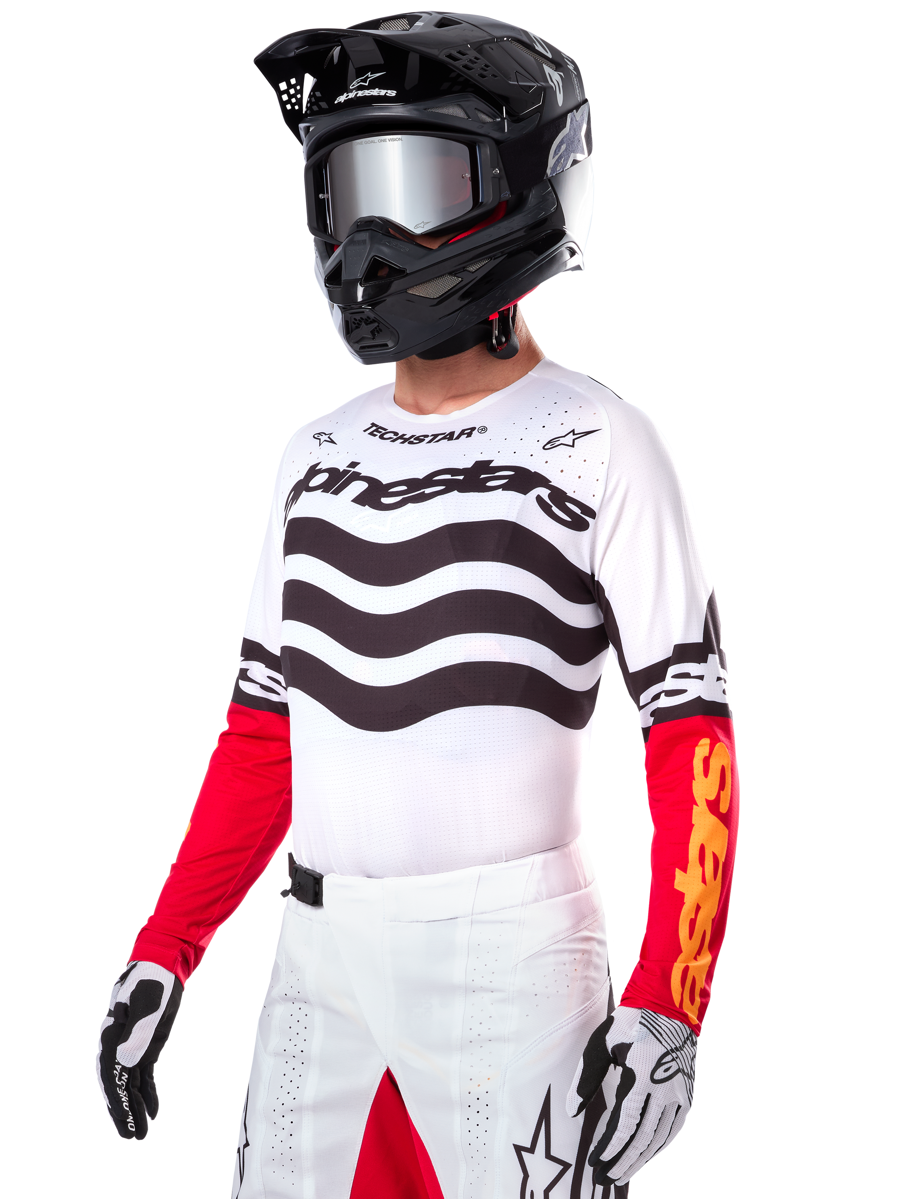 Motocross rider wearing the Alpinestars Limited Edition Techstar Deep Jersey, white jersey featuring black wavy stripes and red lower sleeves, styled with a black helmet, mirrored goggles, white and black gloves, and white racing pants, performance motocross outfit.