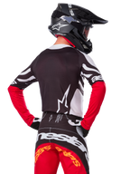 Motocross rider wearing complete racing gear, Alpinestars Limited Edition Techstar Deep Jersey in Black White and High Red, back view, matching Techstar Deep pants, black helmet with goggles, black and white gloves, professional off-road racing outfit