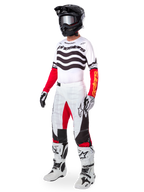 Motocross rider wearing complete racing gear, Limited Edition Techstar Deep Jersey with white and black wavy stripes and red sleeves, matching white and red pants, black helmet, white and black boots, coordinated outfit for off-road racing
