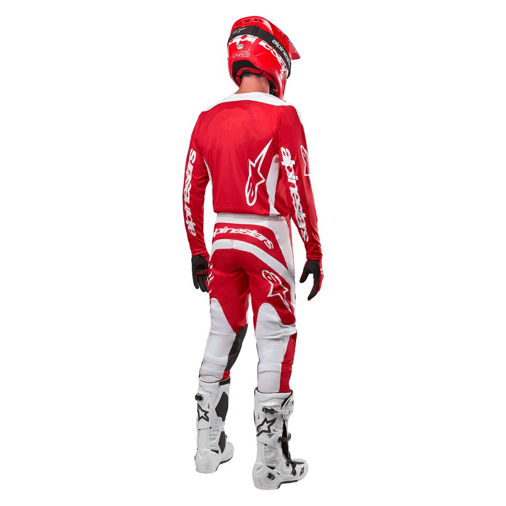 Widok od tyłu zawodnika motocrossowego ubranego w koszulkę Alpinestars 2024 Fluid Lurv w kolorze Mars Red White, zestawioną z dopasowanymi czerwono-białymi spodniami, białymi butami off-road i czerwonym kaskiem, prezentujący design pleców oraz logo Alpinestars.