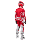 Widok od tyłu zawodnika motocrossowego ubranego w koszulkę Alpinestars 2024 Fluid Lurv w kolorze Mars Red White, zestawioną z dopasowanymi czerwono-białymi spodniami, białymi butami off-road i czerwonym kaskiem, prezentujący design pleców oraz logo Alpinestars.
