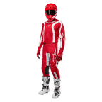 Zawodnik motocrossowy w pełnym stroju wyścigowym, koszulka Alpinestars 2024 Fluid Lurv w kolorze Mars Red i białym, dopasowane czerwone spodnie z białymi akcentami, czerwony kask, czerwone rękawice oraz biało-czarne buty, skoordynowany zestaw do wyścigów off-road