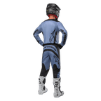 Zawodnik motocrossowy widziany od tyłu w koszulce Alpinestars 2024 Fluid Lurv i pasujących spodniach w kolorze jasnoniebiesko-czarnym, z czarnymi logotypami na plecach i rękawach, czarny kask i białe buty
