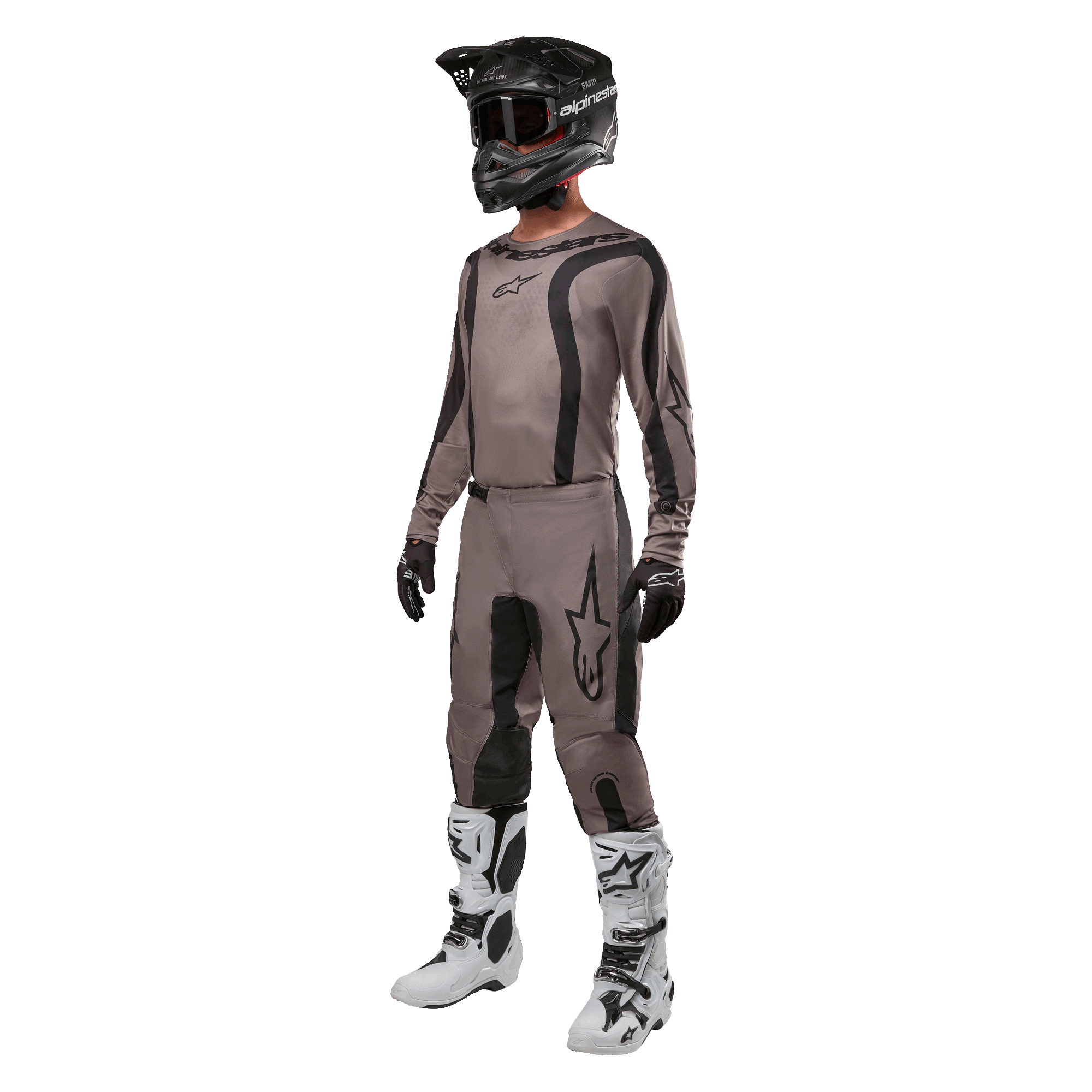 Zawodnik motocrossowy ubrany w pełny strój wyścigowy z koszulką Alpinestars 2024 Fluid Lurv w kolorze Mud Black, w zestawieniu z dopasowanymi spodniami, czarnym kaskiem z goglami, biało-czarnymi butami i czarnymi rękawicami, skoordynowany zestaw do wyścigów terenowych