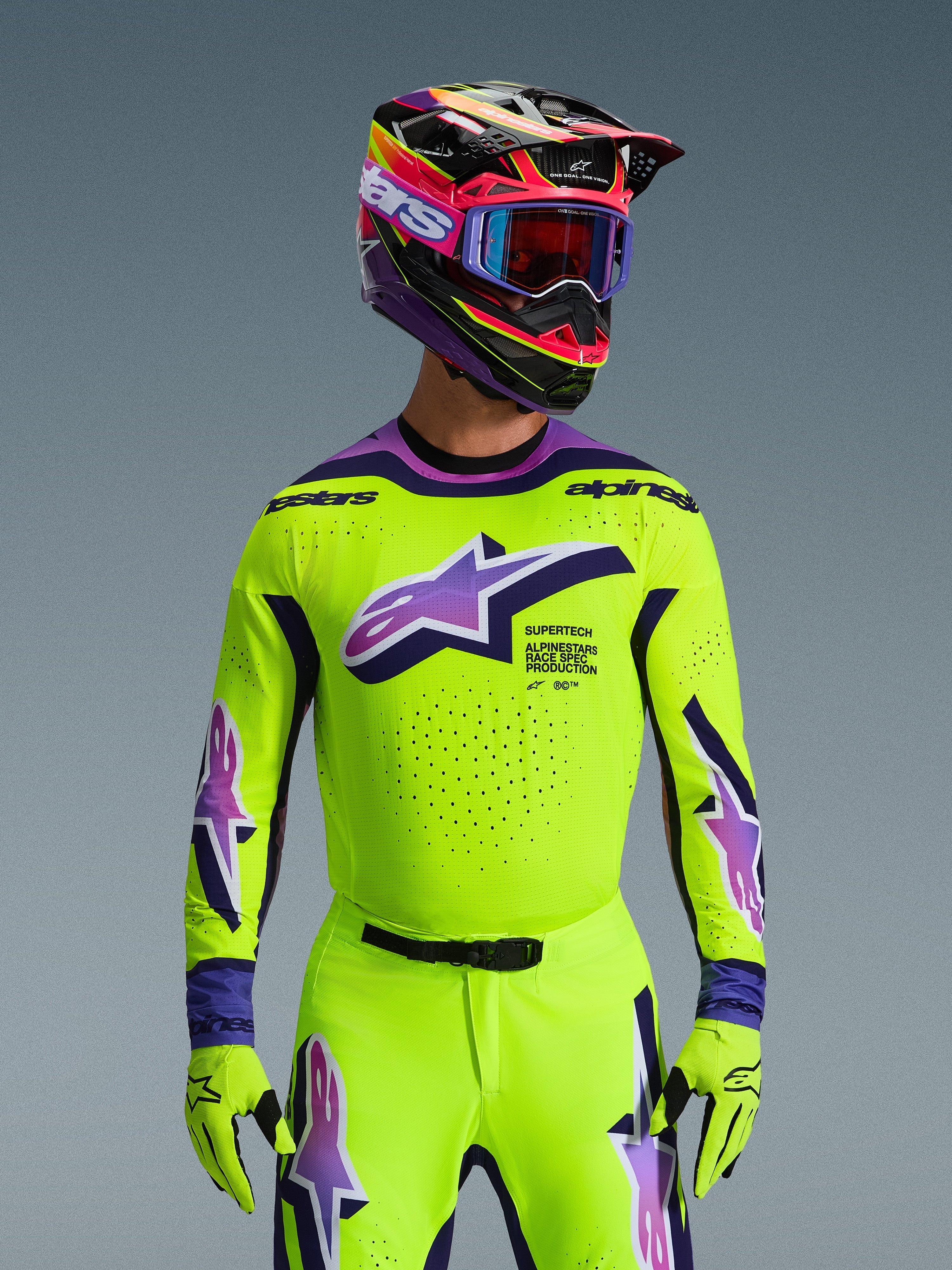 Alpinestars 2026 Supertech Vista Jersey, koszulka motocrossowa, jaskrawy neonowy żółty z fioletowymi i czarnymi akcentami, noszona z dopasowanym kaskiem motocrossowym, goglami i rękawicami, profesjonalny sportowy krój do wyścigów terenowych