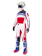 Alpinestars Limited Edition Techstar Fortitude Gear Set, strój motocrossowy, czerwony, biały i niebieski, biała koszulka z wyrazistymi grafikami, pasujące spodnie wyścigowe, biały kask z goglami, dopasowane niebieskie i czerwone buty, profesjonalny sprzęt wyścigowy do jazdy w terenie