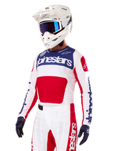 Motocross rider wearing the Alpinestars Limited Edition Techstar Fortitude Jersey, Bright Red White and Blue, featuring a white helmet with blue goggles and matching pants, high-performance racing apparel for off-road competition