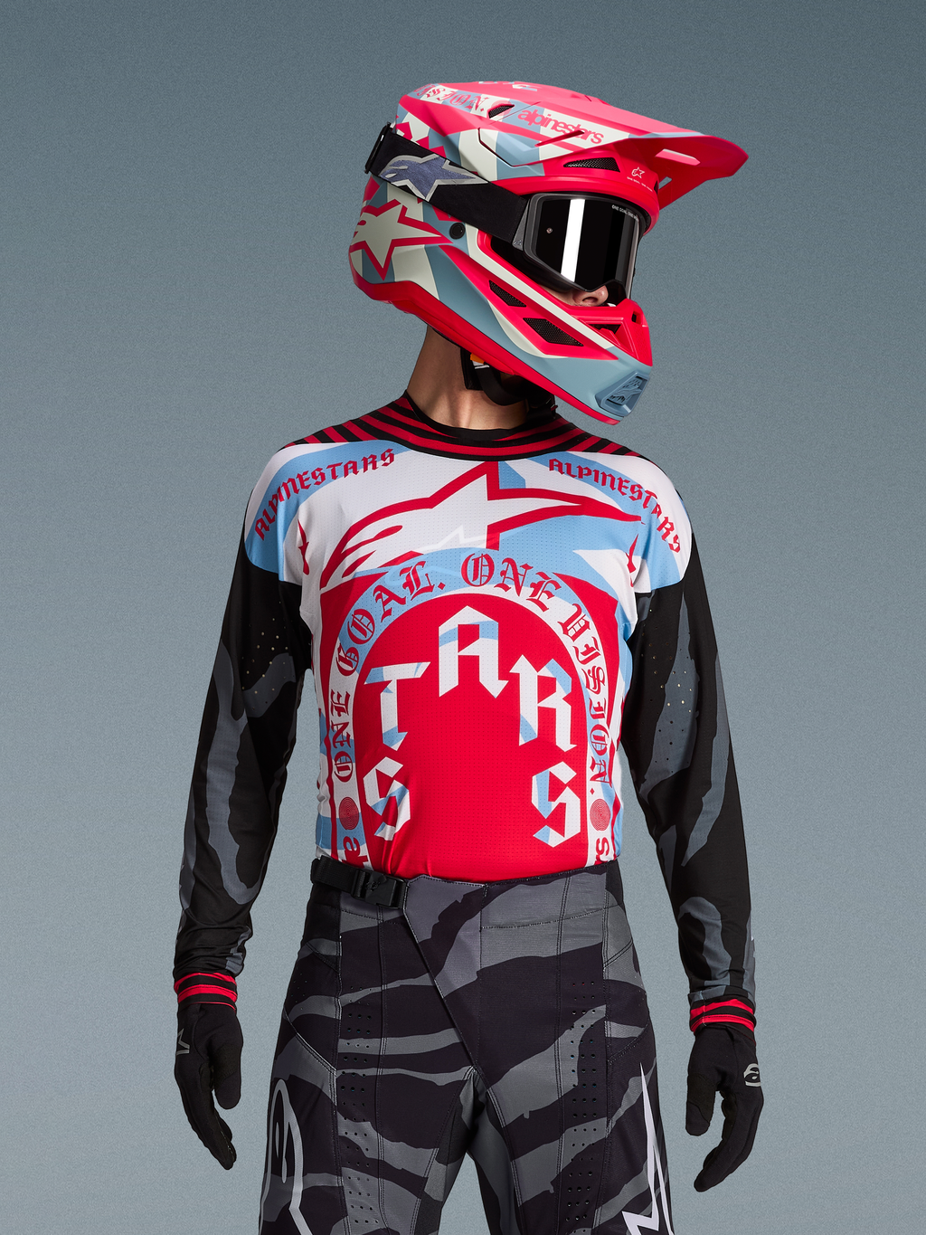 Koszulka Techstar Beast Coast Edycja Limitowana, różowo-niebieski wzór, spodnie w kamuflażu, kask i gogle motocrossowe.