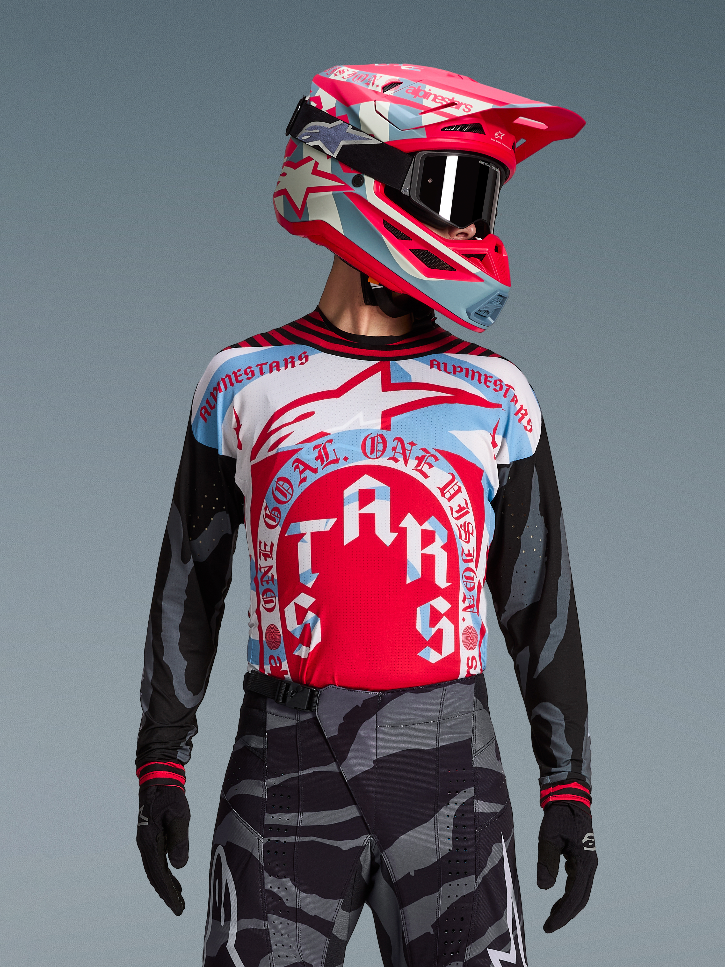 Koszulka Techstar Beast Coast Edycja Limitowana, różowo-niebieski wzór, spodnie w kamuflażu, kask i gogle motocrossowe.