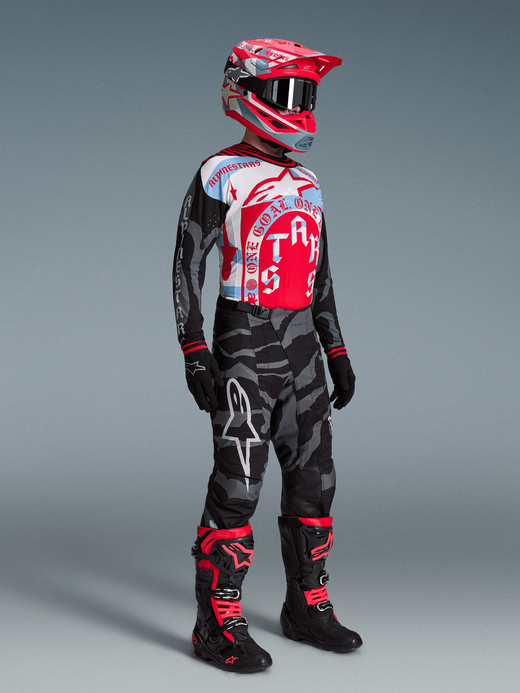 Alpinestars Techstar Beast Coast Edycja Limitowana, koszulka MX, spodnie w kamuflażu, czerwony kask i czarno-czerwone buty.