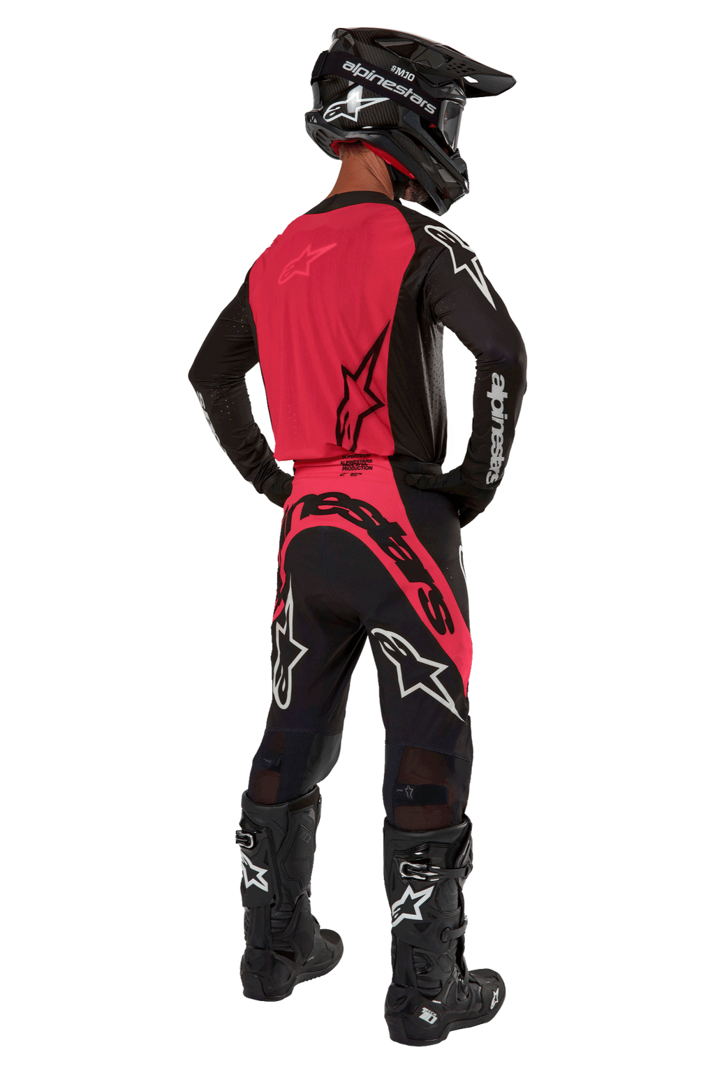 Zawodnik motocrossowy widziany od tyłu w koszulce 2024 Supertech Ward w kolorze Black Red Berry, z jaskrawoczerwonym panelem tylnym i czarnymi rękawami z białym brandingiem Alpinestars. W zestawie z dopasowanymi spodniami motocrossowymi, czarnymi butami Tech 10 i czarnym kaskiem z włókna węglowego, tworzącymi profesjonalny komplet wyścigowy.