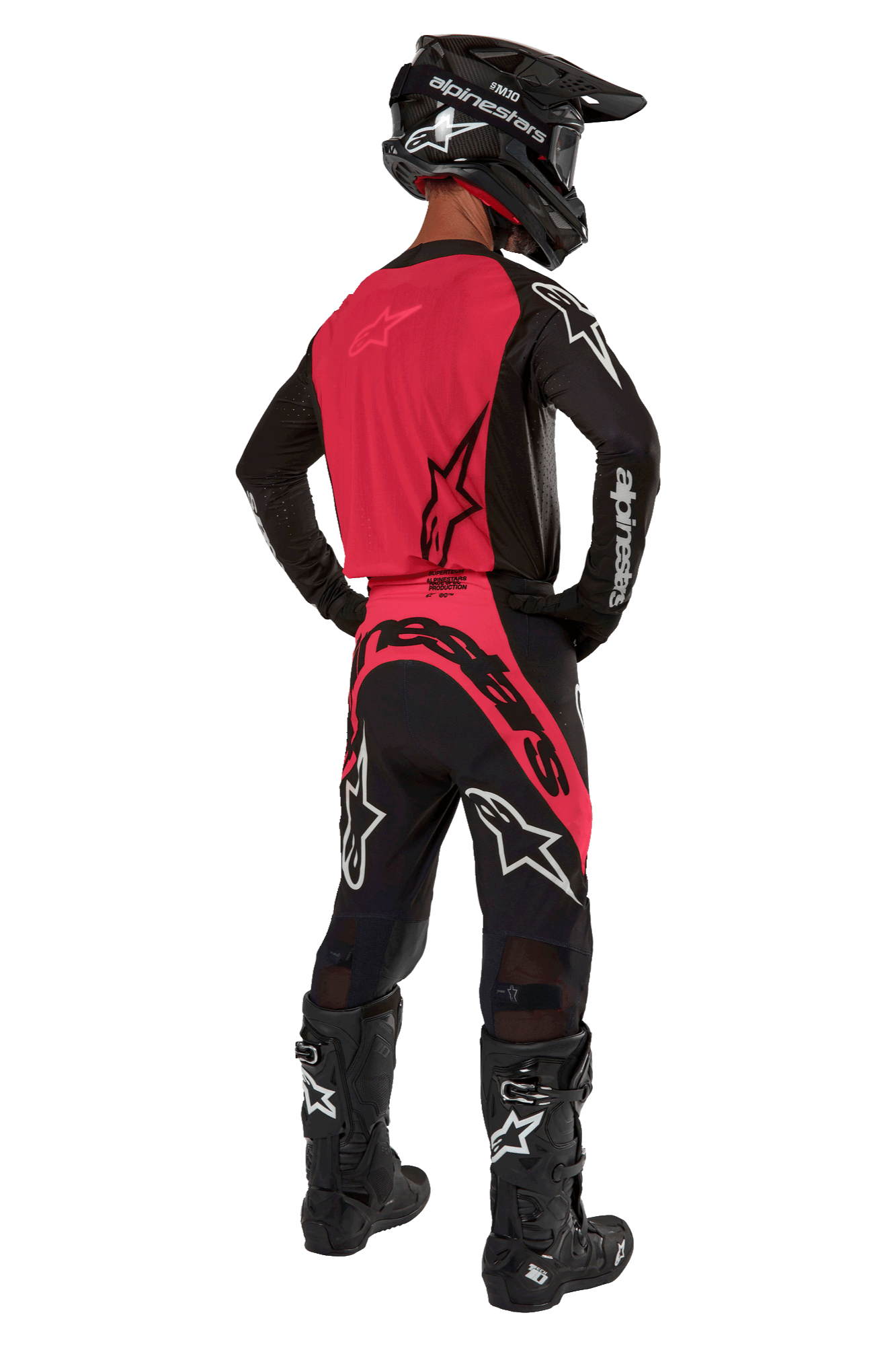 Zawodnik motocrossowy widziany od tyłu w koszulce 2024 Supertech Ward w kolorze Black Red Berry, z jaskrawoczerwonym panelem tylnym i czarnymi rękawami z białym brandingiem Alpinestars. W zestawie z dopasowanymi spodniami motocrossowymi, czarnymi butami Tech 10 i czarnym kaskiem z włókna węglowego, tworzącymi profesjonalny komplet wyścigowy.